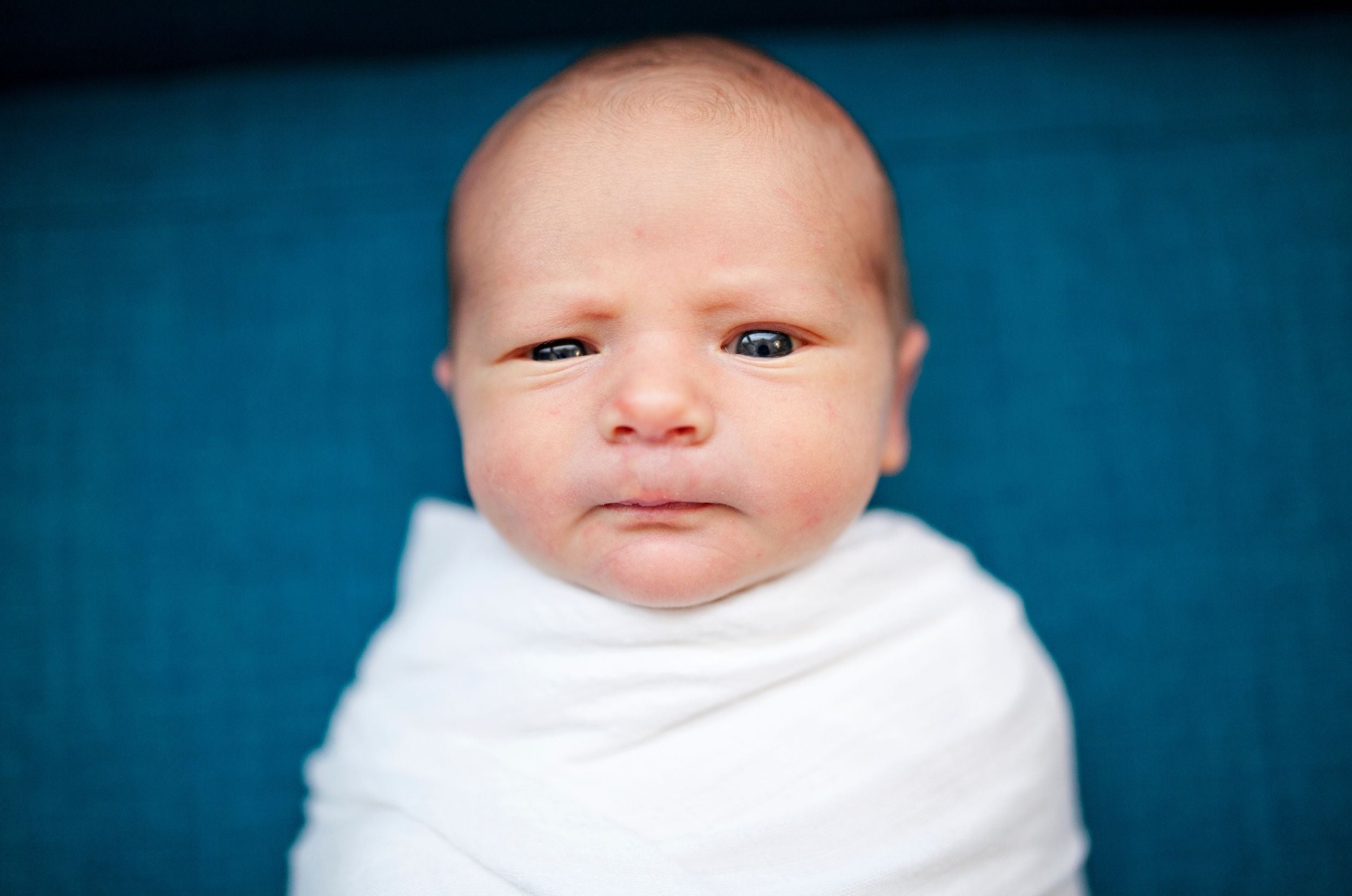 Baby ist wach und gepuckt auf blauer Decke