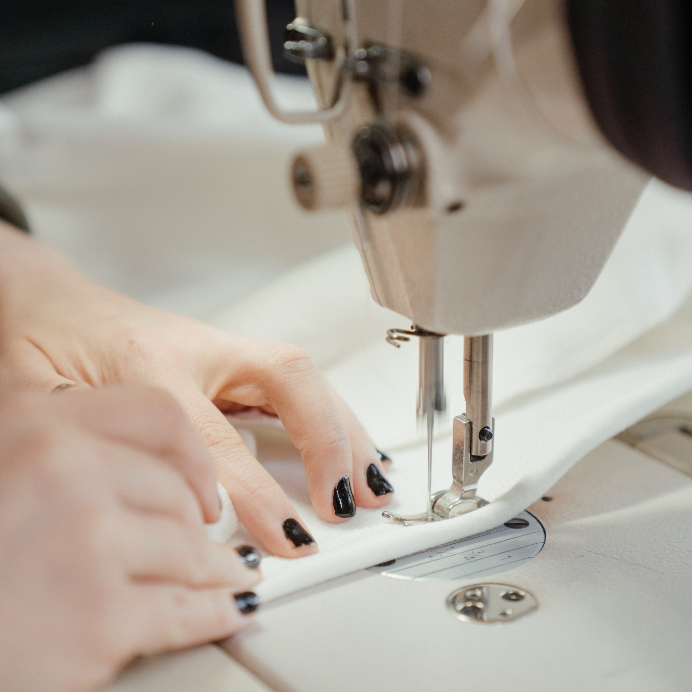 Detailaufnahme einer Hand, die Stoff unter der Nähmaschine führt. Der Text betont Wombagees Philosophie von Qualität, Langlebigkeit und nachhaltigem Handwerk statt kurzlebiger Trends.