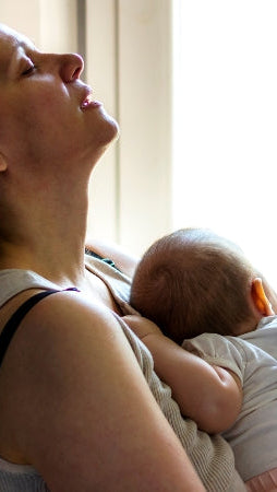erschöpfte Mutter trägt Baby im Arm